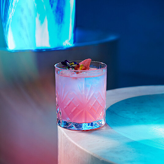 Kleines Whiskeyglas mit einem rosa-weißen Cocktail im Raum "Waterfall" bei Eatrenalin Late Night.