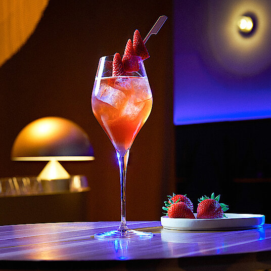 Hohes, gewölbtes Champagnerglas mit einem lecker-beerigen Welcome-Drink bei Eatrenalin Late Night.