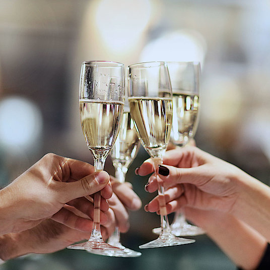 Four people toast with champagne glasses